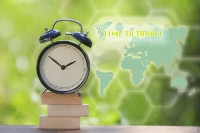 Digital composite image of alarm clock on books by world map