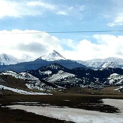 Scenic view of snowcapped mountains against cloudy sky