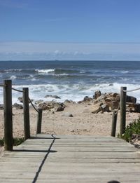 Wooden posts on beach against sky