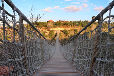 Footbridge amidst trees against sky