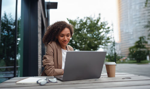 Businesswoman using laptop while sitting on table