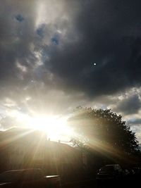 Low angle view of sun shining through clouds