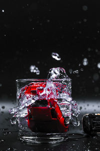 Close-up of red water splashing in glass against black background