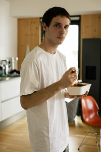 Portrait of young man holding meal box while standing at home