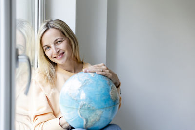 Portrait of young woman holding globe at home