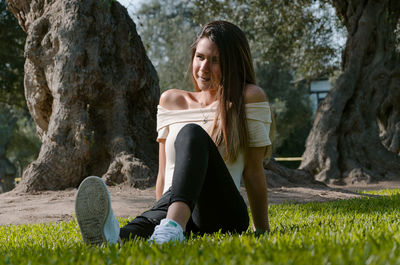 Woman sitting on tree trunk