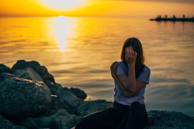 Side view of woman looking at lake during sunset