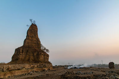 Rock formations on land against sky during sunset