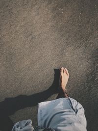 Low section of man relaxing on sand at beach