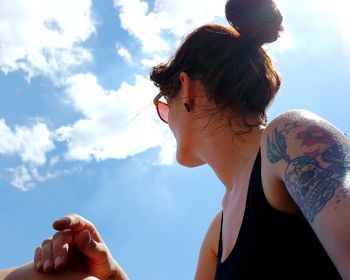 Low angle view of woman wearing sunglasses against sky