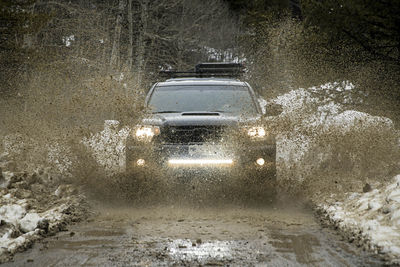 Off-road car splashing dirt on road during winter