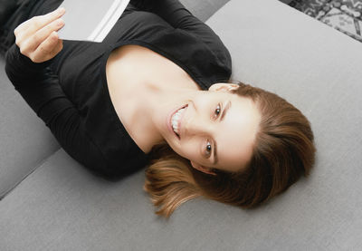 High angle portrait of woman reading book while lying on bed at home