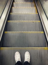 Low section of man standing on escalator