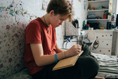 Teenage girl doing homework while sitting in the room.