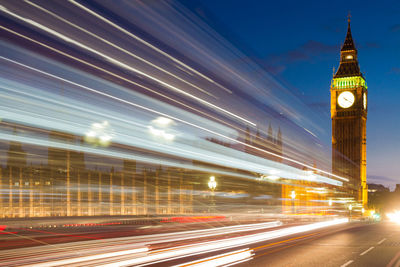 Light trails on road against buildings at night