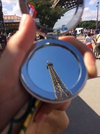Close-up of woman holding mirror with reflection of eiffel tower