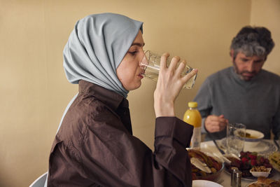 Woman in headscarf drinking water at dinner