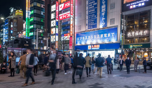 People walking on illuminated street against buildings at night