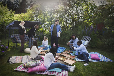 Multi-ethnic friends having snacks during summer party at yard