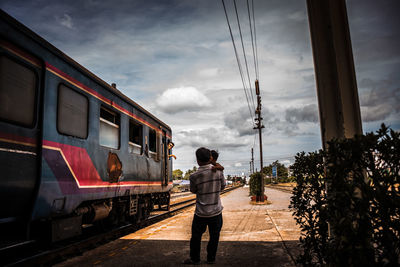 Rear view of man standing on train against sky