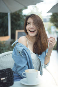 Portrait of smiling young woman sitting at cafe