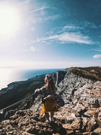 Woman on rock by sea against sky