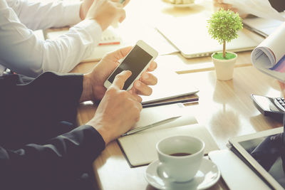 Midsection of woman holding coffee cup on table