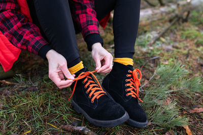 The girl sits on a log in the forest and ties her shoelaces. travel, hiking and hiking concept