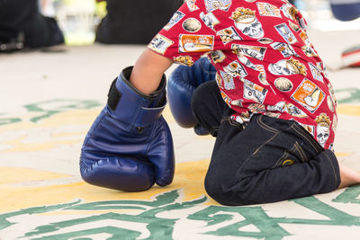 Low section of boy wearing boxing gloves playing at home