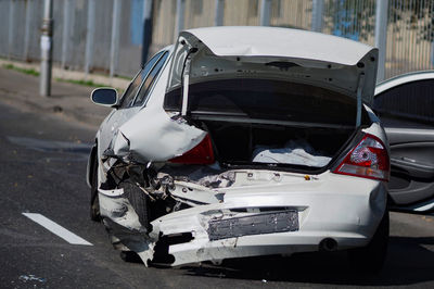 White passenger car crashed in an accident stands in the middle of the road