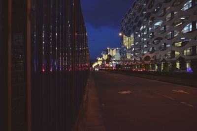 Illuminated street amidst buildings in city at night