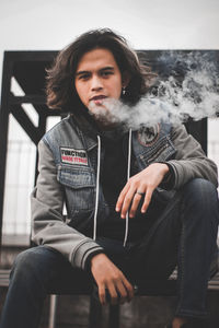 Portrait of young man sitting outdoors, enjoying his life.