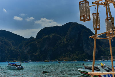 Boats moving in river against mountains