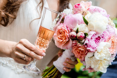 Midsection of bride with bouquet having drink