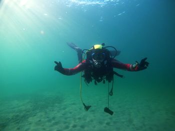 Diver floating in clear cold wate lake with sun