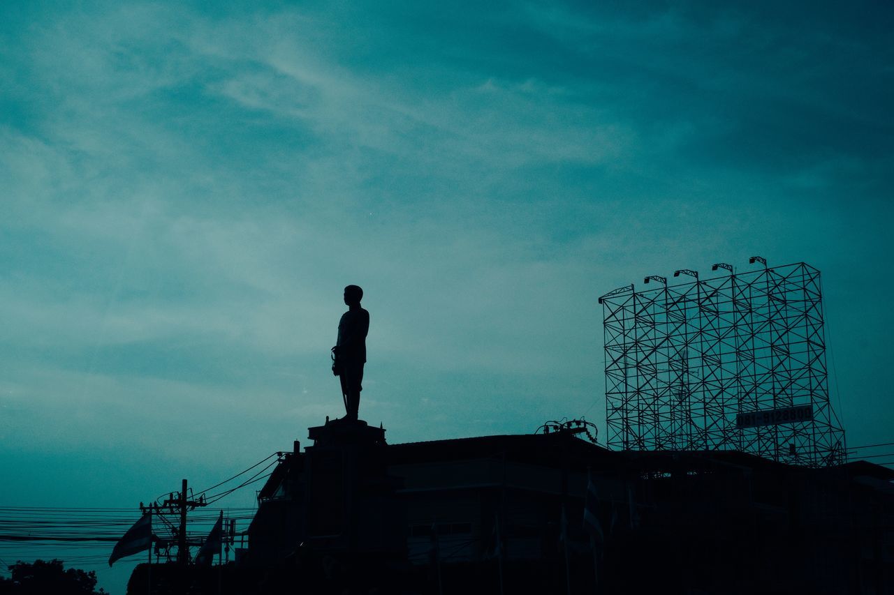 LOW ANGLE VIEW OF SILHOUETTE MAN STANDING AGAINST BUILDING