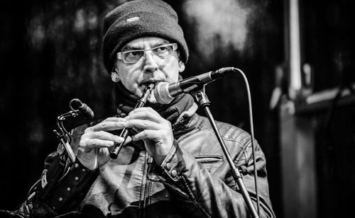 Portrait of man playing flute on stage in black and white 