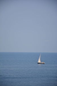 Sailboat sailing on sea against clear sky