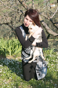 Portrait of smiling woman with dog on field