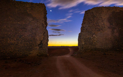 Dirt road against sky during sunset