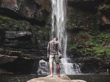 Man standing on rock formation in water