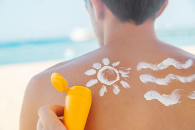 Midsection of man with umbrella on beach