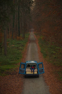 Woman sleeping in motor home amidst trees in forest