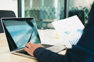 Midsection of man using laptop on table