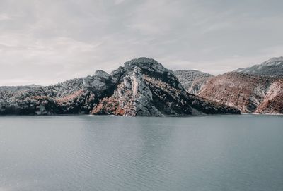 Scenic view of lake by mountains against sky