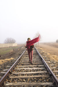 Front view of a woman with scarf walking on a rail road