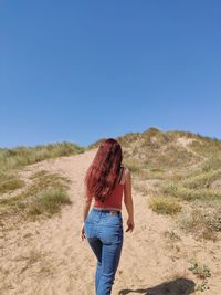 Rear view of woman standing on land against sky