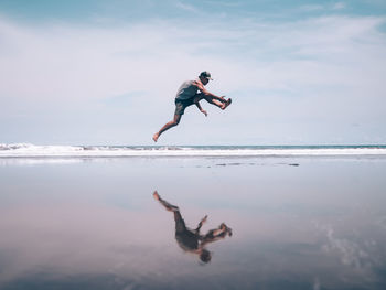 Full length of man jumping in sea against sky