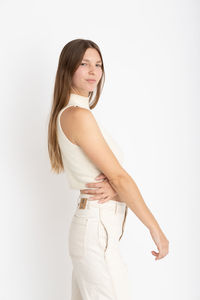 Portrait of young woman standing against white background