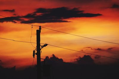 Low angle view of silhouette electricity pylon against sky during sunset